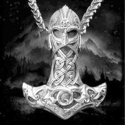 Wikinger Thors Hammer Anhänger, silberfarben, mit keltischen Mustern, vor Bergkulisse.