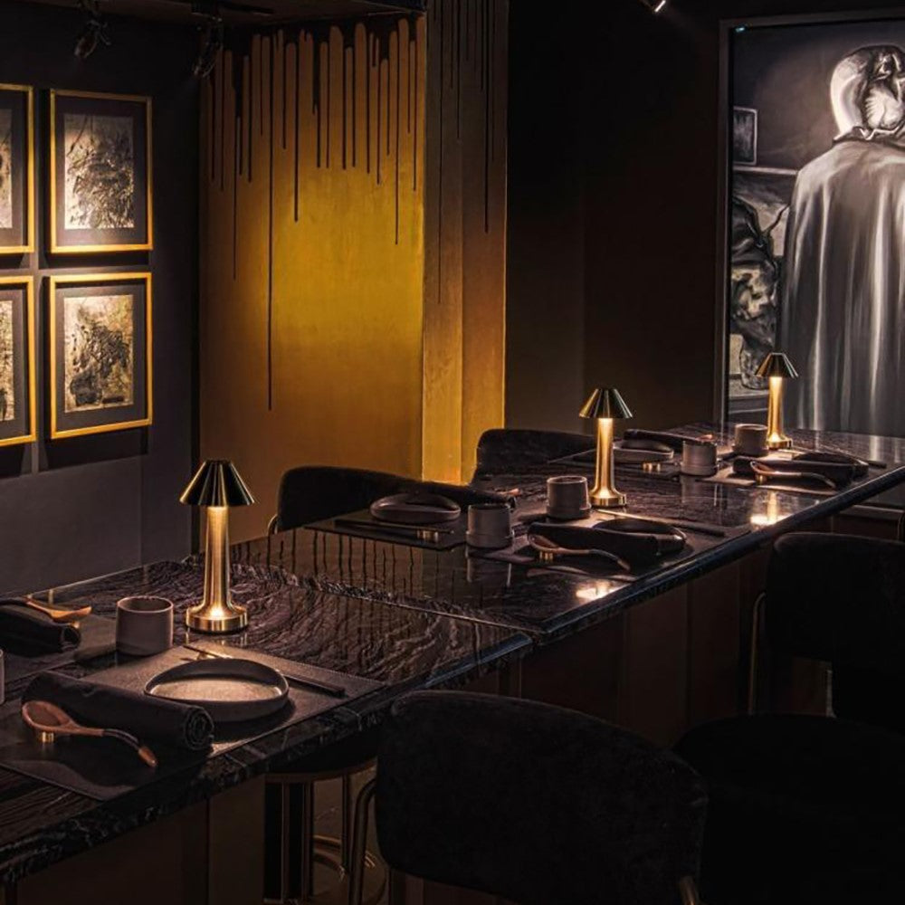 Elegantes Restaurant-Interieur mit dunklem Marmortisch, goldenen Lampen und Kunstwerken an der Wand.