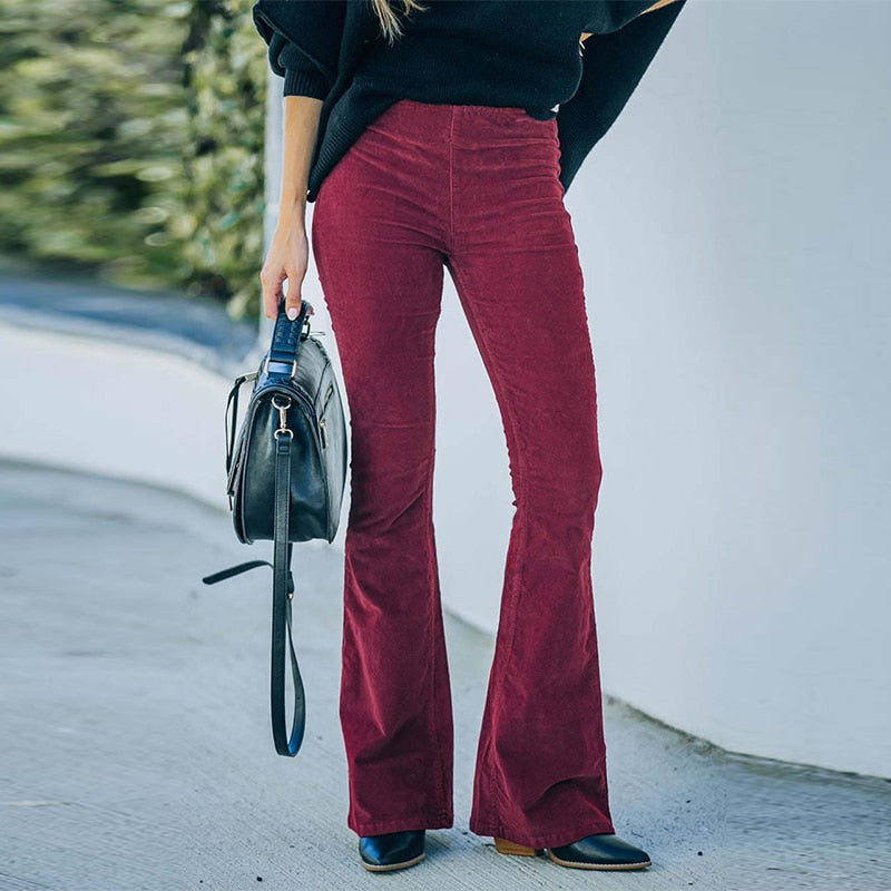Frau in roten Schlaghosen aus Cord, schwarze Tasche, Herbstmode, stilvoll, lässig.