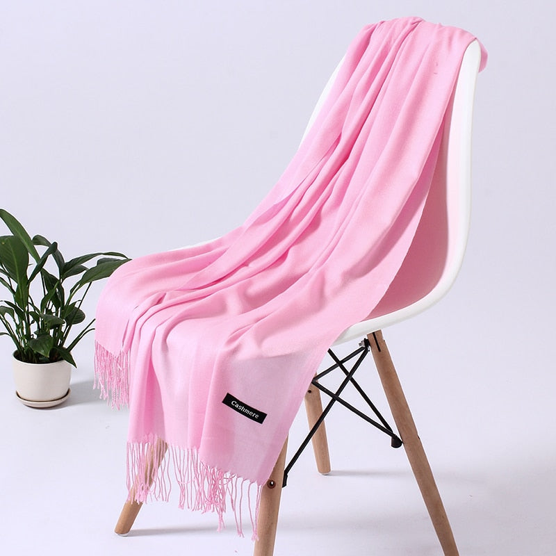 Rosa Kaschmirschal auf weißem Stuhl, weiches Material, modisches Accessoire, Wohnzimmerdekor.