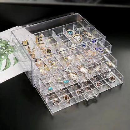 Klarer Acryl-Schmuck-Organizer mit mehreren Fächern für Ohrringe und Ringe auf schwarzem Tisch.