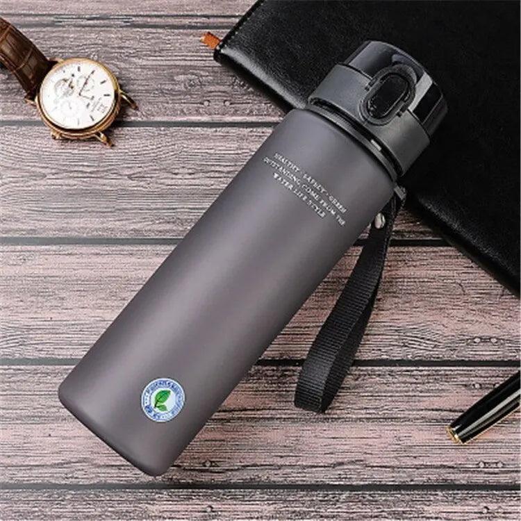 Graue Edelstahl-Wasserflasche mit Deckel, 500ml, auf Holztisch, ideal für Outdoor-Aktivitäten.