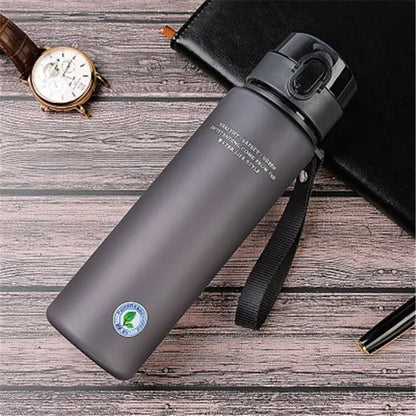 Graue Edelstahl-Wasserflasche mit Deckel, 500ml, auf Holztisch, ideal für Outdoor-Aktivitäten.