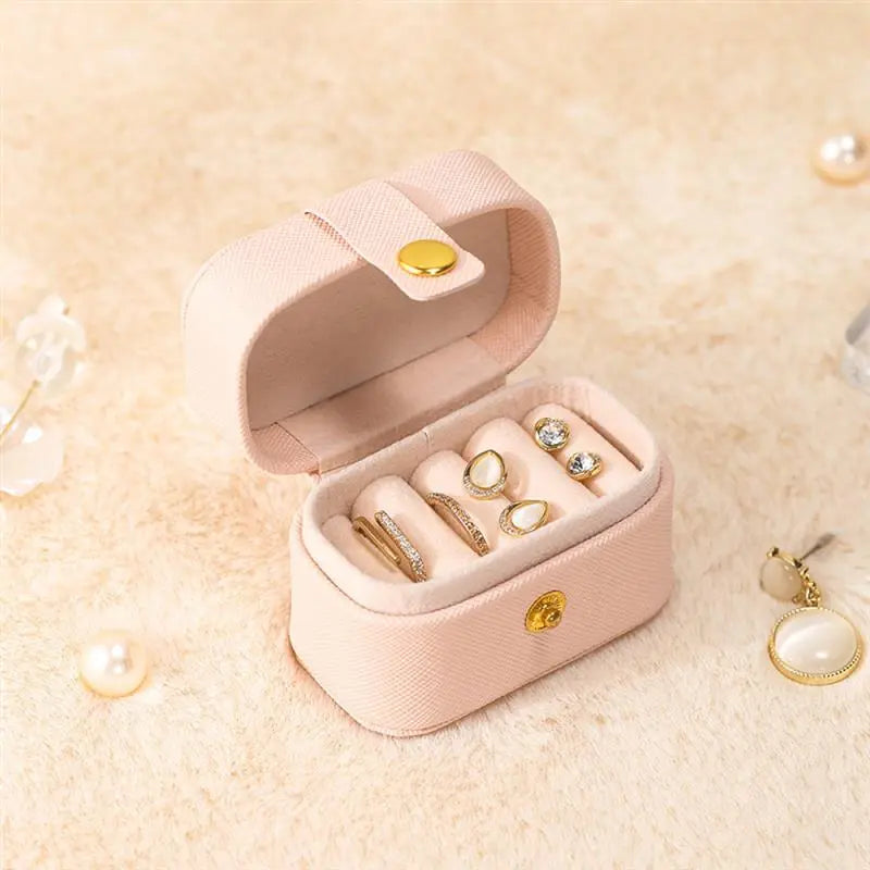 Rosa Schmuckkästchen mit goldenen Ringen, kompakt, ideal für Reisen, elegantes Design.