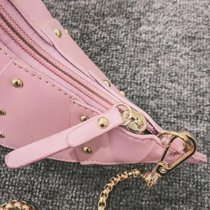 Rosa Lederhandtasche mit goldenen Nieten und Reißverschluss auf grauem Hintergrund.