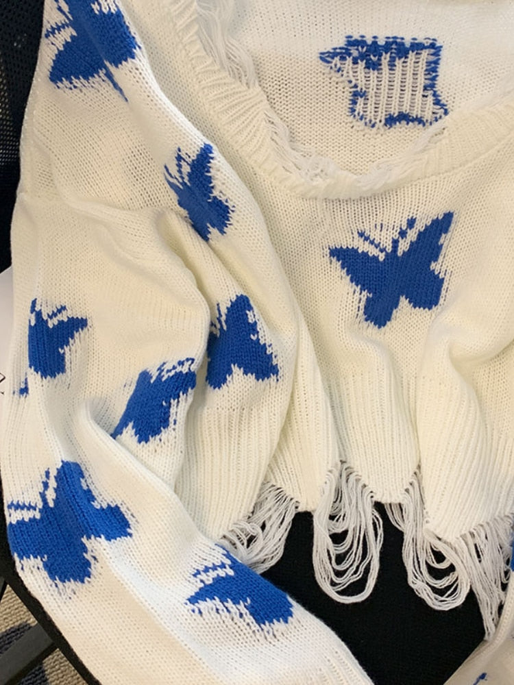 Weiße Strickdecke mit blauen Schmetterlingen und Fransen, gemütlich, dekorativ, Baumwolle.