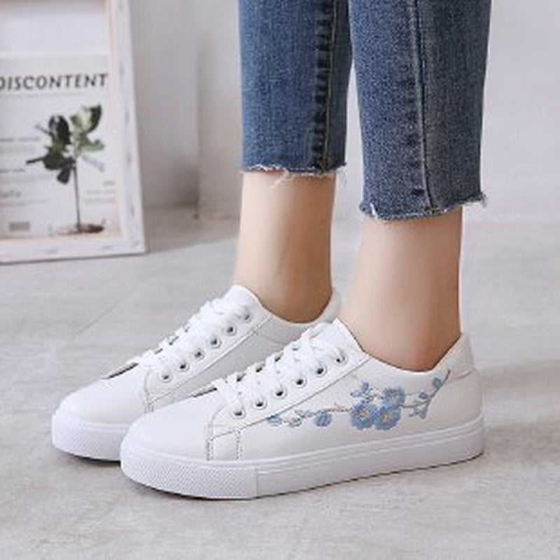 Weiße Damen-Sneaker mit blauer Blumenstickerei, Freizeitschuhe, Jeans, Modeaccessoire.