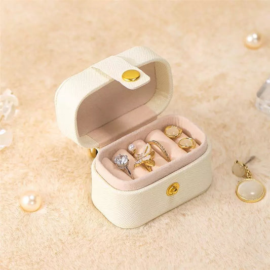 Beige Schmuckkästchen mit goldenen Ringen, Samtfutter, tragbar, elegant, Schmuckaufbewahrung.