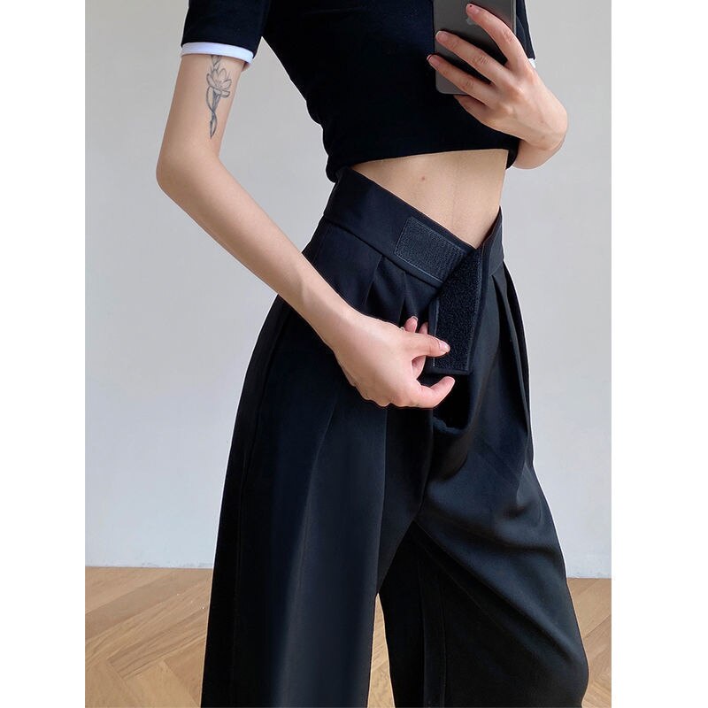 Frau in schwarzer, weiter Hose und schwarzem Crop-Top, zeigt Taillenverschluss.