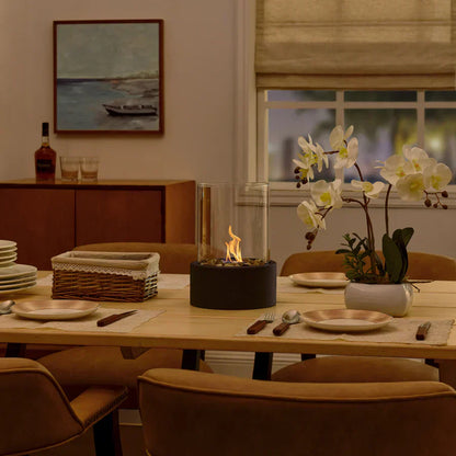 Tischkamin Glaszylinder auf Esstisch, moderne Deko, gemütliche Atmosphäre, Wohnzimmer.