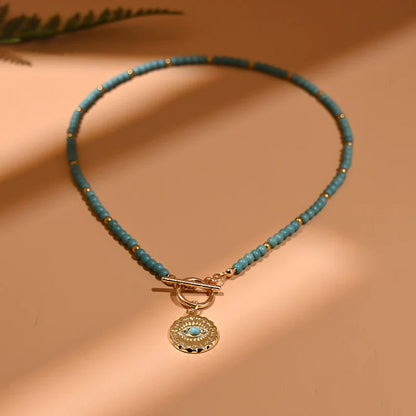 Türkisfarbene Perlenkette mit goldfarbenem Anhänger, eleganter Schmuck für Damen.
