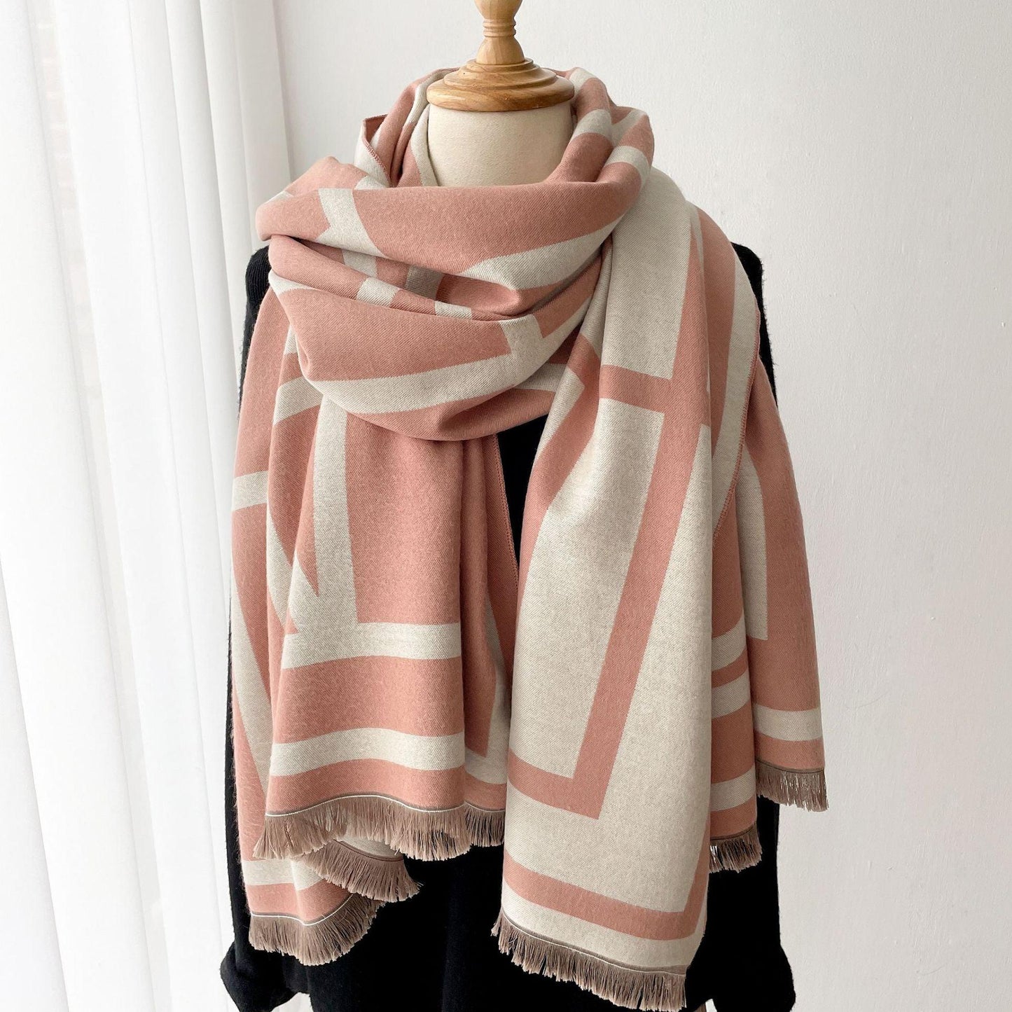 Rosa-weißer Wollschal mit geometrischem Muster auf schwarzem Mantel, modisches Accessoire.