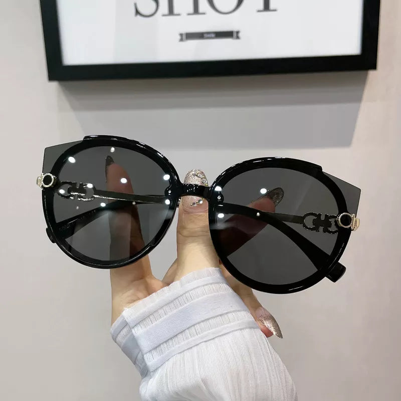 Schwarze Designer-Sonnenbrille mit runden Gläsern und goldenen Details, modisch und elegant.