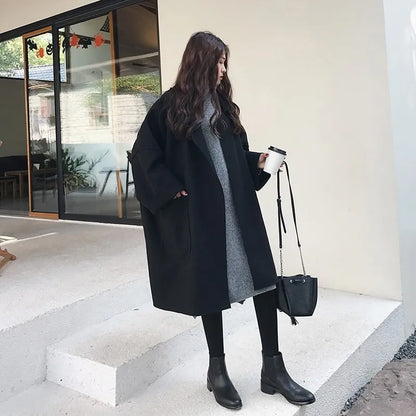 Frau in schwarzem Wollmantel, grauem Kleid, hält Kaffeebecher, modisch, Herbstmode.