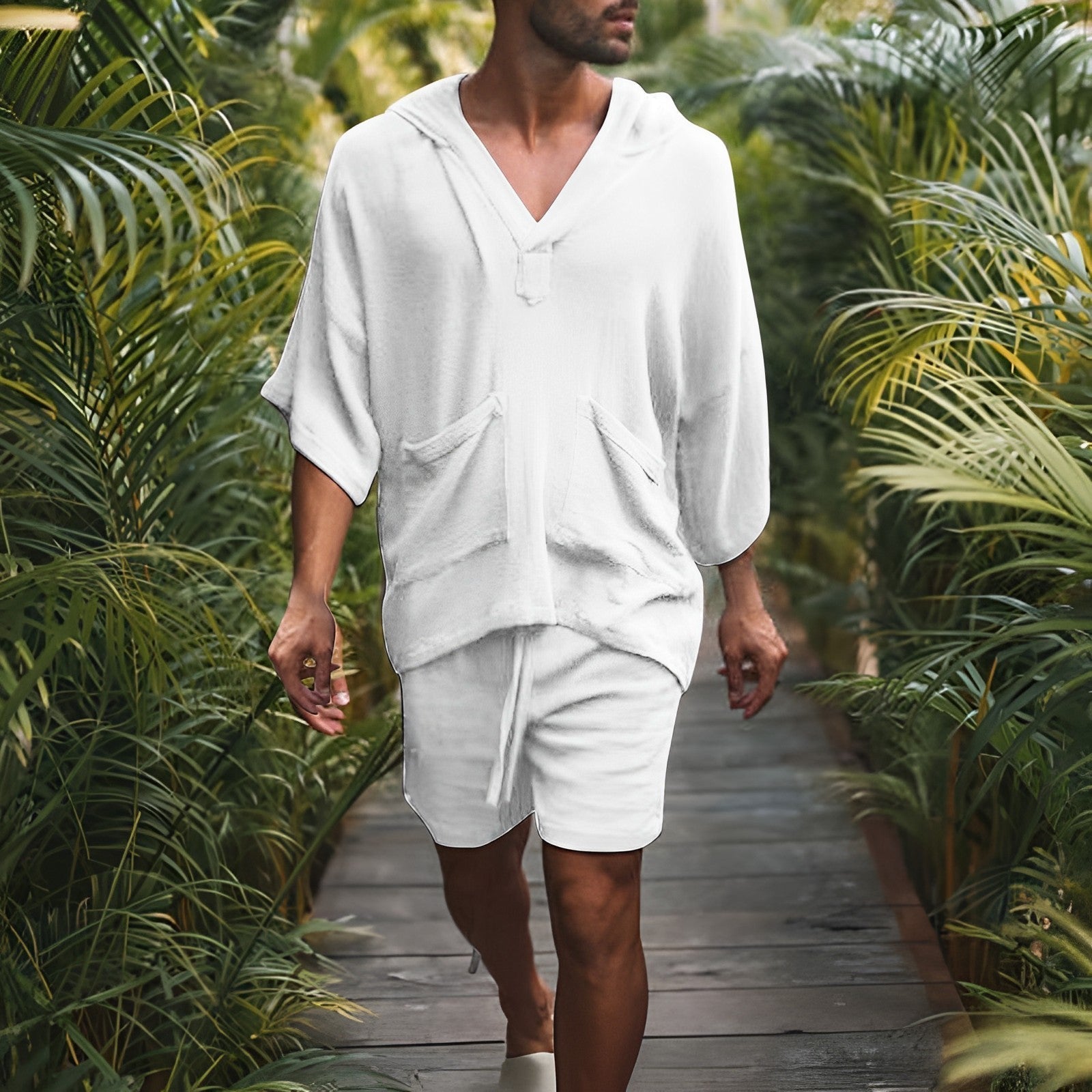 Mann in weißem Kapuzenpullover und Shorts, Spaziergang im tropischen Garten.