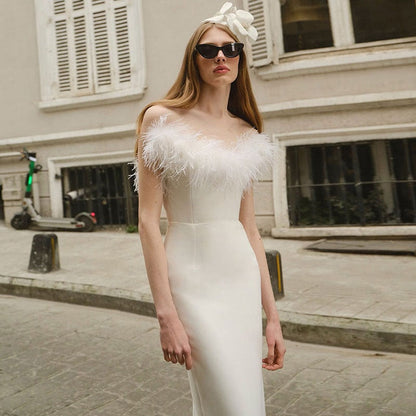 Frau in elegantem weißen Abendkleid mit Federn, Sonnenbrille, Blumenhaarschmuck, Stadtstraße.
