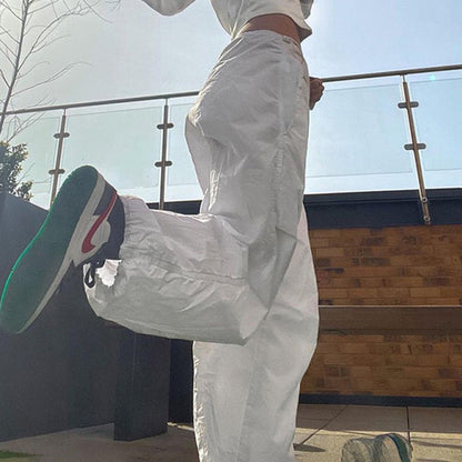 Weiße Jogginghose, Nike-Sneaker, Frau, sportlich, urbaner Stil, Freizeitmode, Sonnenschein.