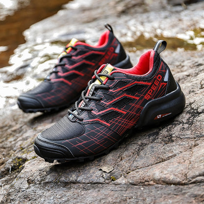 Schwarze und rote Outdoor-Laufschuhe mit rutschfester Sohle auf Felsen.
