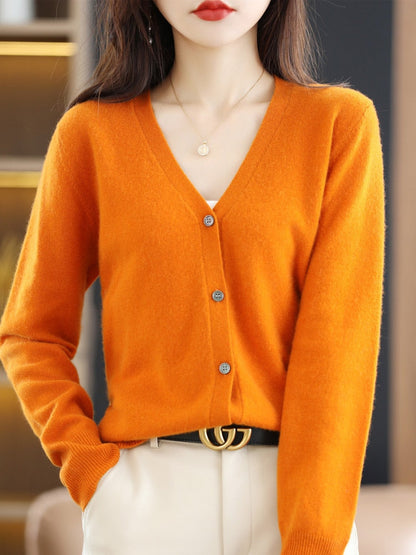 Frau in orangefarbener Strickjacke, V-Ausschnitt, Knöpfe, eleganter Herbstlook, Damenmode.
