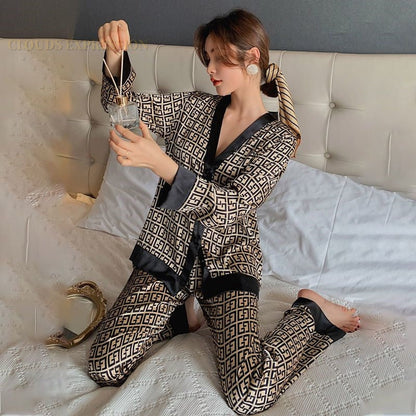Frau in gemustertem Pyjama auf Bett, hält Teetasse, luxuriöse Nachtwäsche, beige und schwarz.
