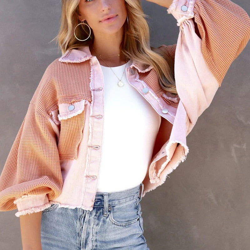 Frau in rosa Patchwork-Jacke mit Ballonärmeln, weißem Top und Jeans.