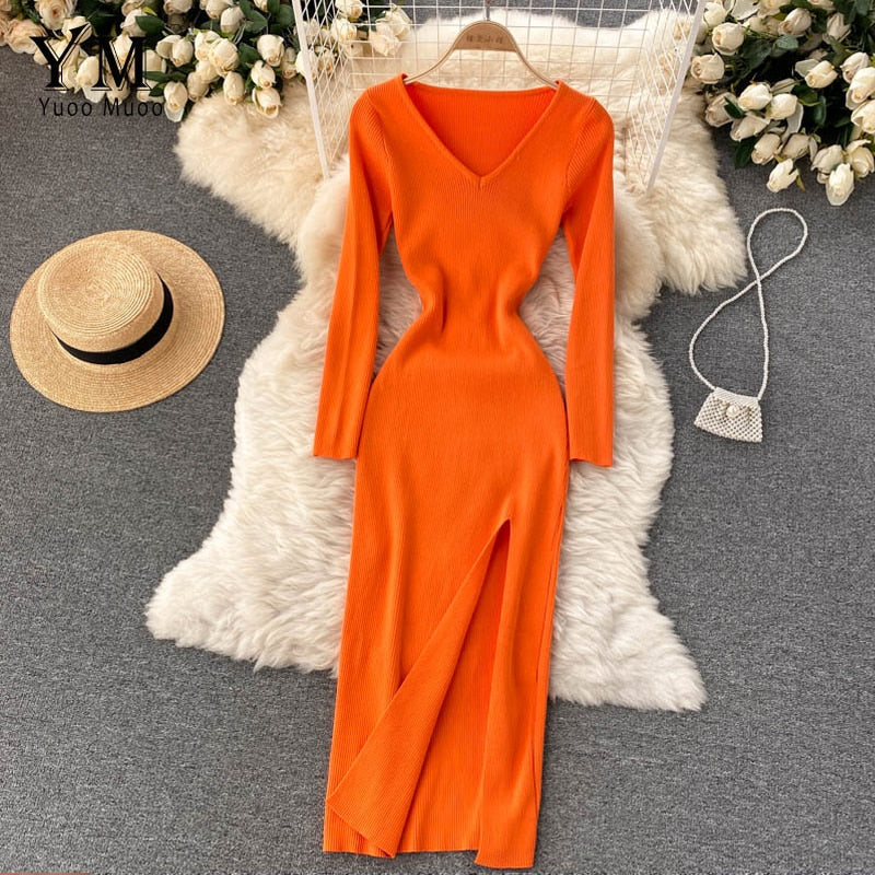 Orangefarbenes Strickkleid mit V-Ausschnitt, Langarm, auf weißem Fellteppich, elegantes Design.