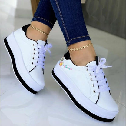 Weiße Plateau-Sneaker mit Blumenstickerei, Damenmode, Freizeitschuhe, Jeanshintergrund.