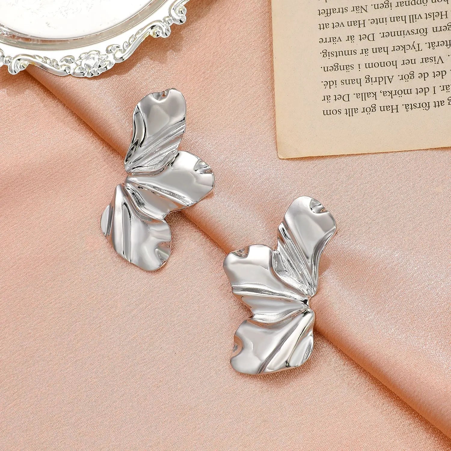 Silberne Ohrringe in Schmetterlingsform auf rosa Stoff, eleganter Schmuck für Damen.