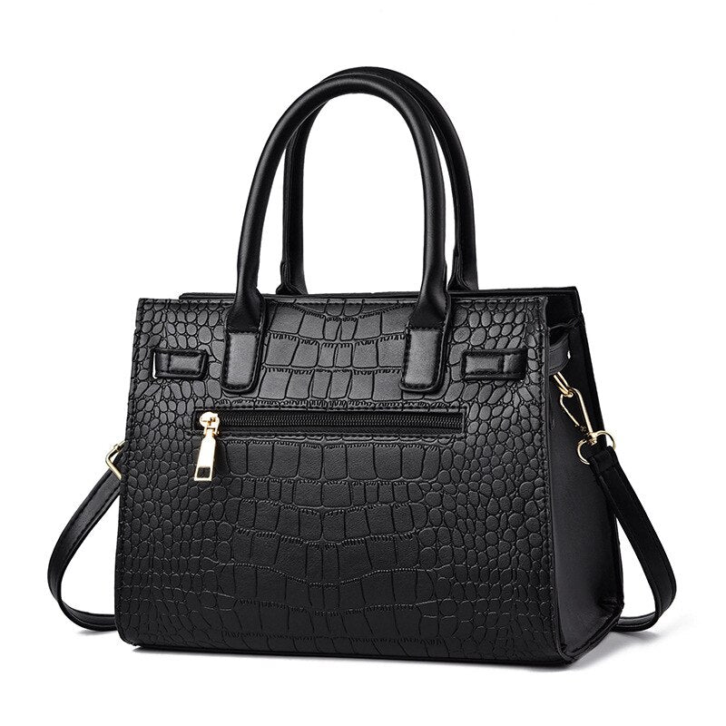 Schwarze Damenhandtasche aus Kunstleder mit Krokodilprägung und abnehmbarem Schulterriemen.