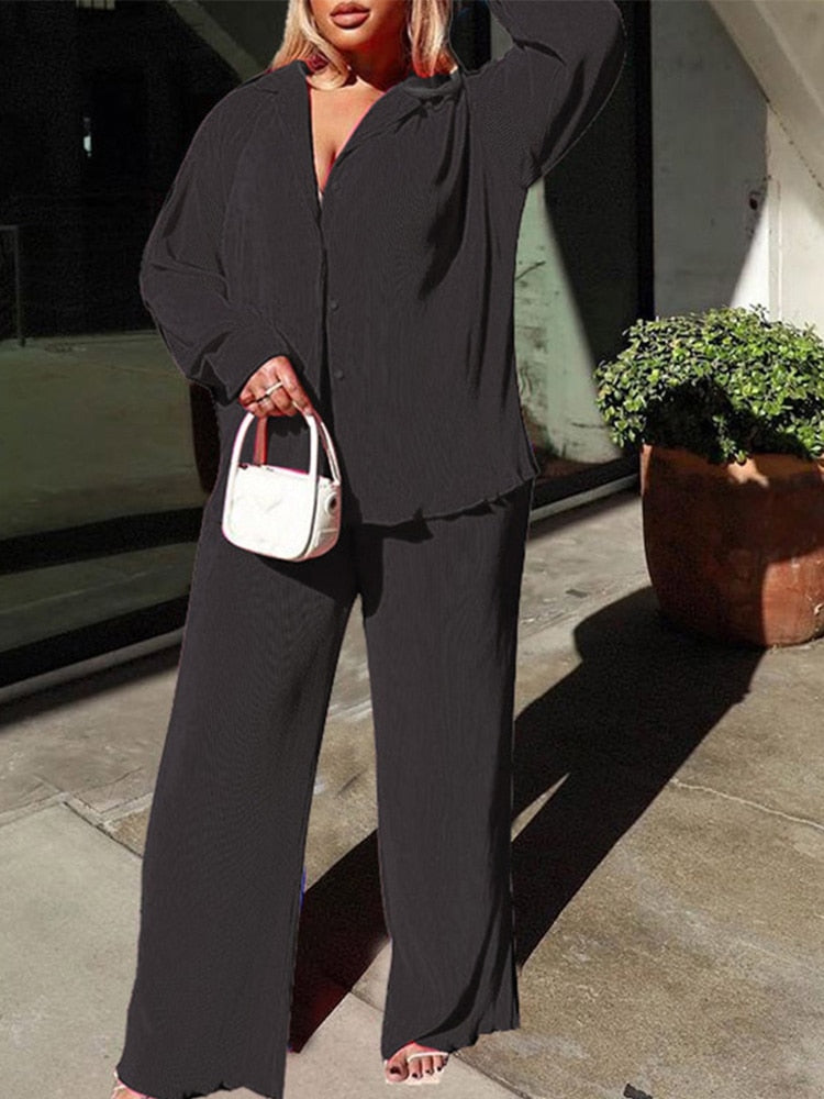 Frau in schwarzem Hosenanzug mit weißer Handtasche, draußen stehend, Mode, Plus-Size.