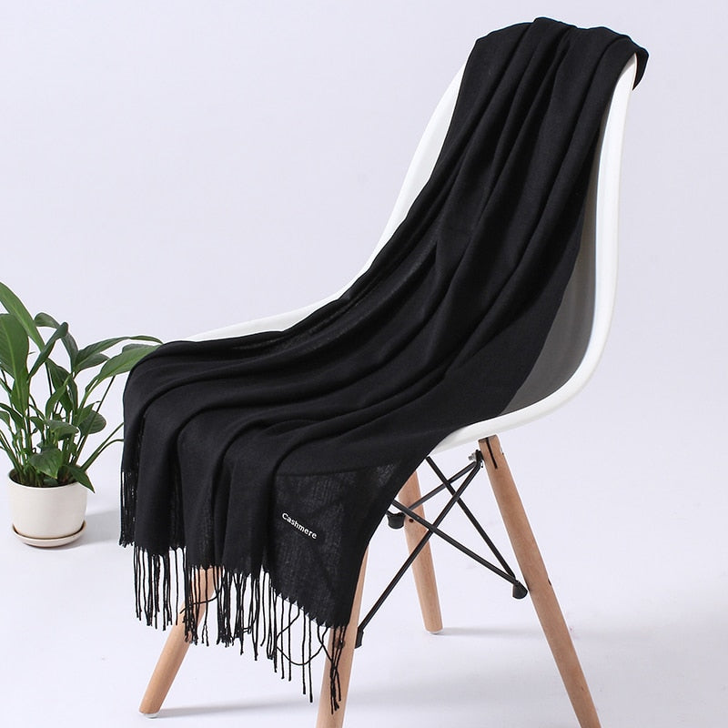 Schwarzer Kaschmirschal auf weißem Stuhl, elegantes Design, weiches Material, Fransen.