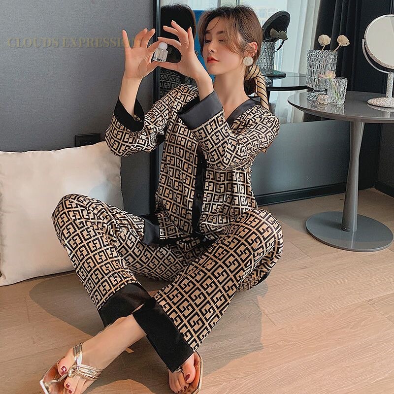 Frau in gemustertem Pyjama, schwarz-beige, sitzt auf Boden, modernes Schlafzimmer, Spiegel.