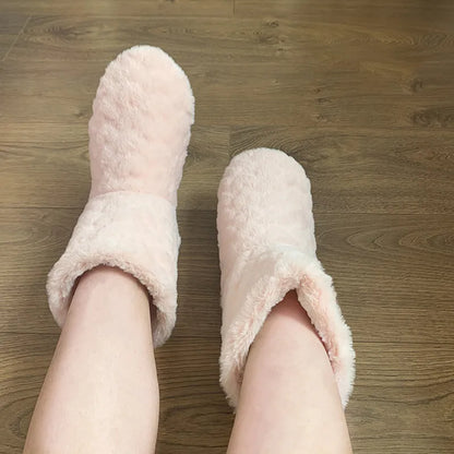 Rosa Plüsch-Hausschuhe auf Holzfußboden, gemütliche Winter-Fußbekleidung für Damen.