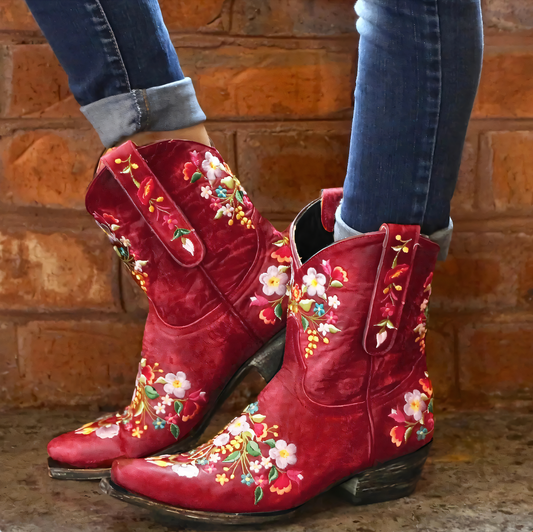 Rote Cowboystiefel mit Blumenstickerei, Damenmode, Leder, vor Ziegelwand, Jeans hochgekrempelt.