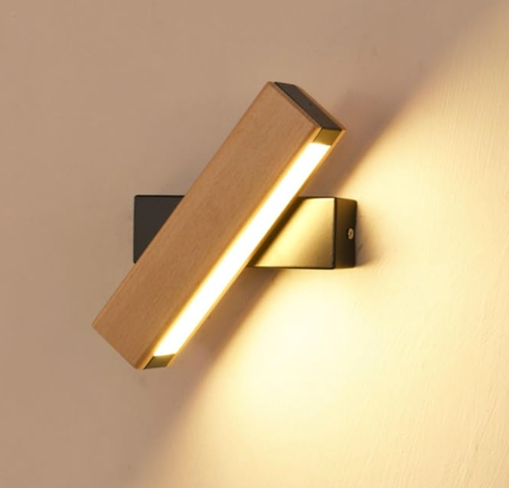 Närbild på tänd träarmatur med svart fäste, vriden i vinkel och lyser varmt över en beige vägg. 7