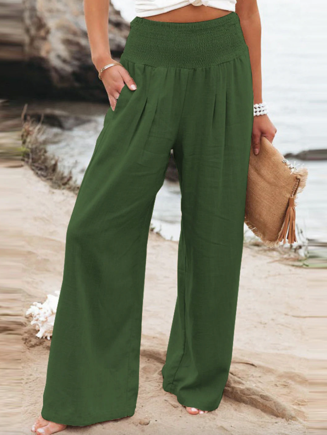 Frau in grüner Leinenhose am Strand, Sommermode, weite Passform, lässiger Stil.