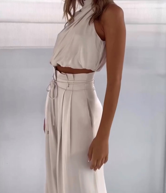 Frau in eleganter, cremefarbener, ärmelloser Bluse und Hose, modisches Damenoutfit.