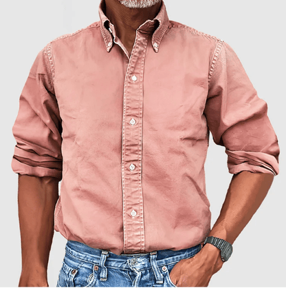 Mann in rosa Button-Down-Hemd aus Baumwolle, hochgekrempelte Ärmel, blaue Jeans.