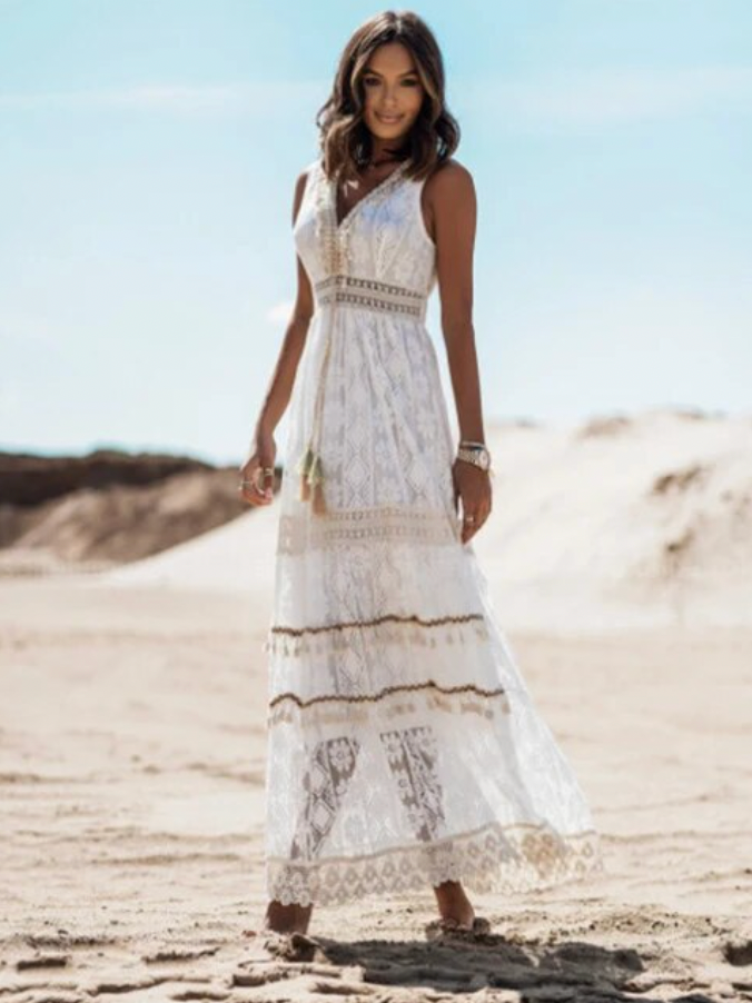 Frau im weißen Spitzenkleid am Strand, Sommermode, elegantes Maxikleid, Boho-Stil.