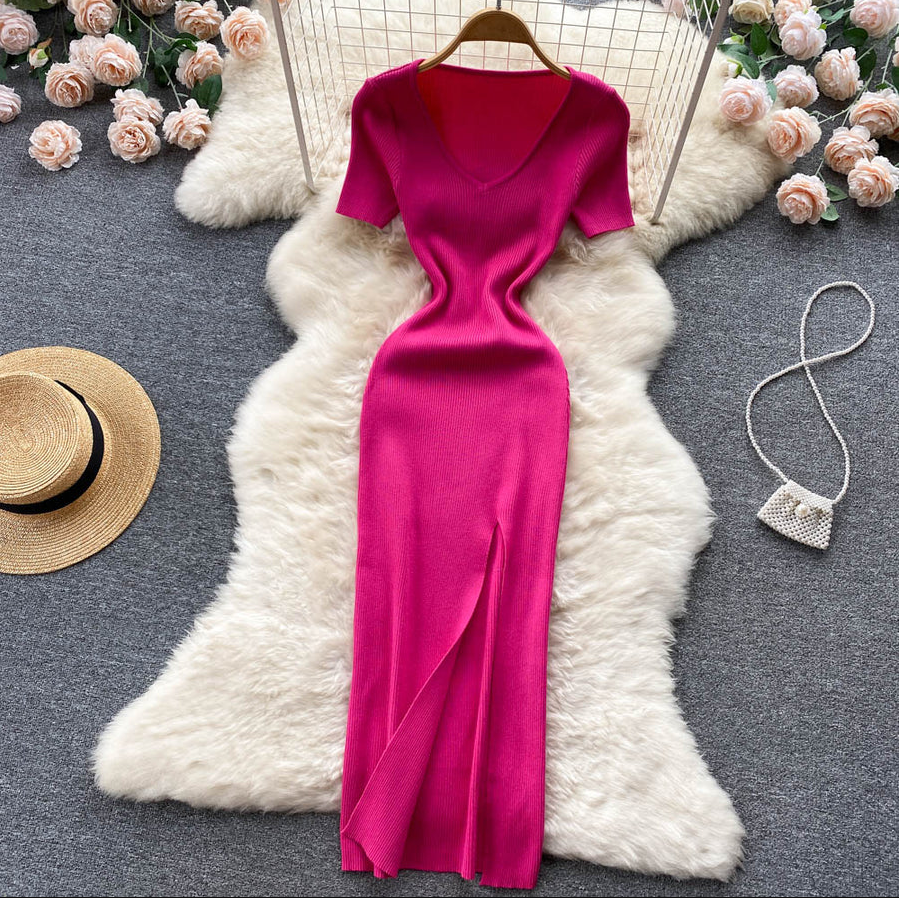 Pinkfarbenes Strickkleid mit V-Ausschnitt, kurze Ärmel, auf weißem Fell, umgeben von Rosen.