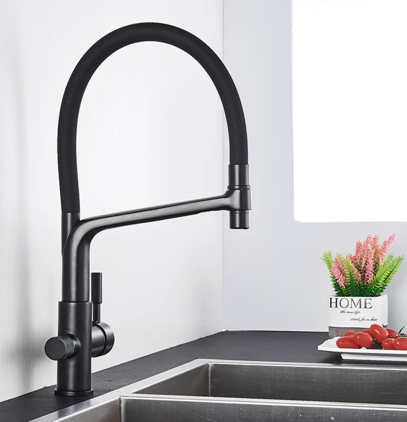 Schwarzer Küchenarmatur, gebogener Auslauf, Edelstahl, modernes Design, neben Spüle.