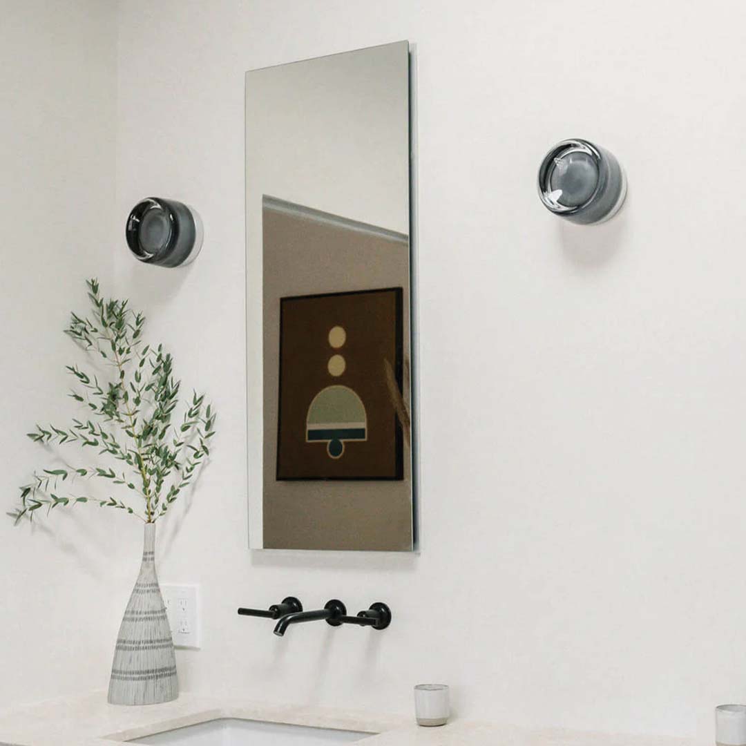 Moderner Badezimmer-Wandspiegel mit schwarzem Wasserhahn und dekorativer Vase auf weißem Waschtisch.