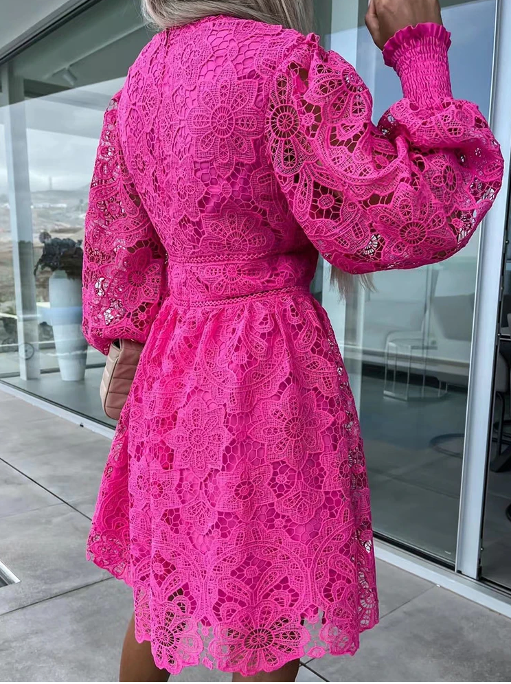 Frau in pinkem Spitzenkleid mit langen Ärmeln, draußen auf einer Terrasse.