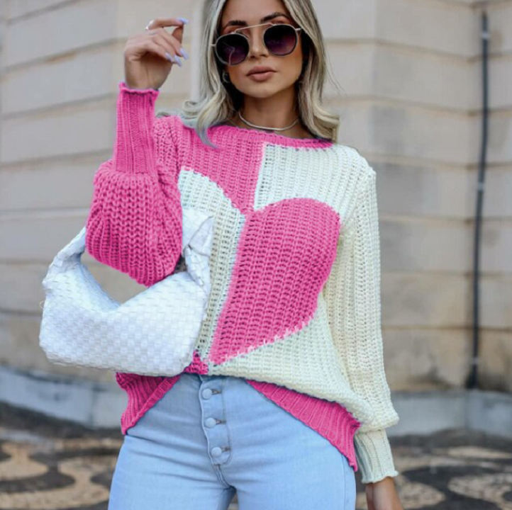 Frau in rosa-weißem Herz-Pullover, blauer Jeans, Sonnenbrille, weiße Tasche, modisch.
