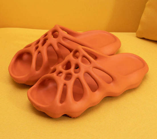 Orange 3D-gedruckte Sandalen, atmungsaktiv, rutschfest, modisch, auf gelbem Hintergrund.