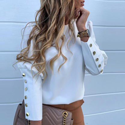 Frau in weißer Bluse mit goldenen Knöpfen, braune Tasche, blonde Haare, modisches Outfit.
