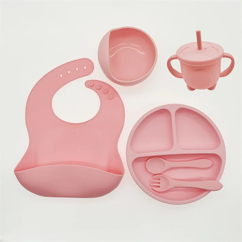 Rosa Silikon-Babygeschirr-Set mit Lätzchen, Teller, Becher, Schüssel und Besteck.