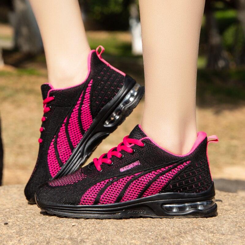 Schwarze und pinke Damen-Laufschuhe mit Luftpolstersohle auf einem Steinweg.