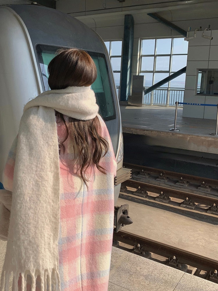 Frau mit pastellfarbenem Schal am Bahnhof vor Zug, Wintermode, Reisende, Rückansicht.