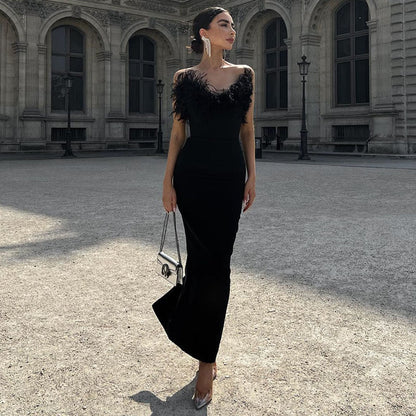 Frau in elegantem schwarzem Abendkleid mit Federn, steht vor historischer Architektur.